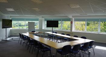One half of the Taw and Torridge meeting room, configured with tables, chairs, flipcharts and two large television screens for presentation use.