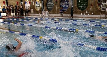 Photo of swimming pool lanes with people swimming in them, making a splash
