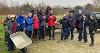Photo of a group of volunteers, holding wheelbarrows, shovels and rakes