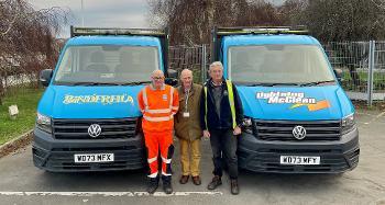 Councillor Chris Leather and two members of the Waste and Recycling team stood in between the two vans, with Binderella on the left and Lightening McClean on the right