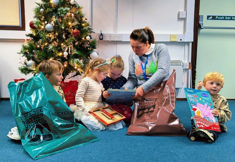 Children Ava, Rosa, Reggie, Oakley and Teresa from the Recycling team sat together on the floor with recycling bags