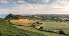 Picture of fields along the coast with a cloudy blue sky background.