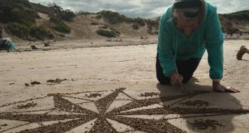 A person drawing in the sand, creating a big star.