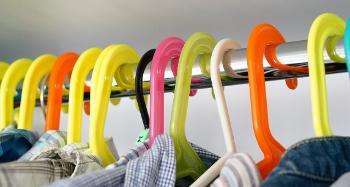 Picture of the tops of multiple coloured clothes hangers, hanging on a clothes rail.