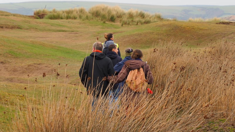 A panoramic view on the Northam Burrows in winter with a small group of people walking away from the camera wearing warm coats