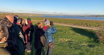 Group of people looking across the estuary as part of their guided walk, birdspotting.