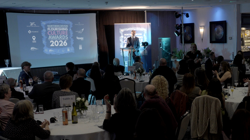 A photo of the presentation evening at the Flourshing Culture Awards, with many people sat around tables and someone presenting at the front. 