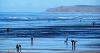 A photo of Westward Ho! beach with blue sky and blue waters, a variety of people on the beach